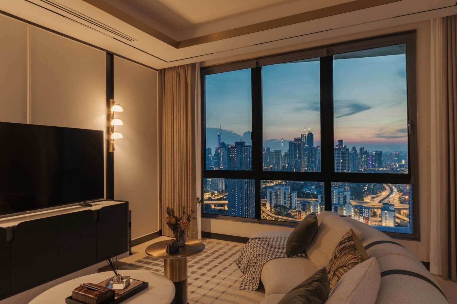 Type D2 show unit living room at dusk with the Kuala Lumpur skyline beyond — show unit photograph